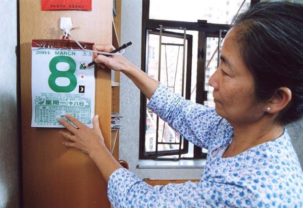 A woman marking a calendar at home using a pencil