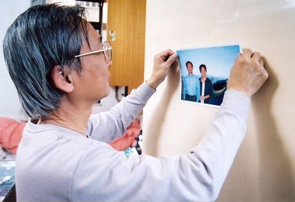 A man sticking a photo on a wall at home