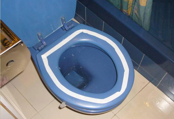 A blue toilet bowl with white tape sticked onto the toilet seat, forming a white circle
